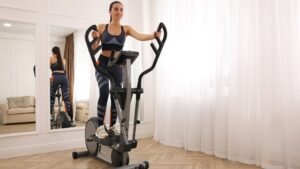moteris sportuojantis su elipsiniu treniruokliu namuose